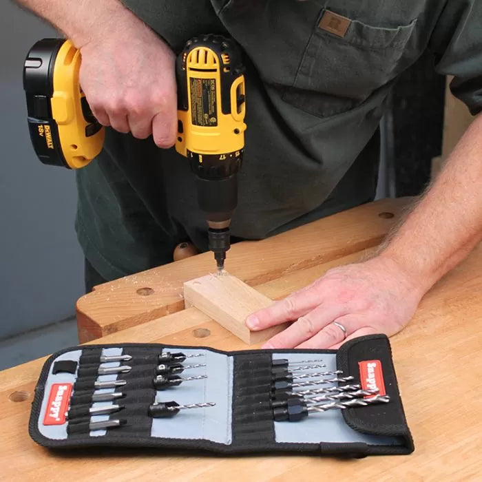 Person using a cordless drill and drill bit set on a wood block at a workbench