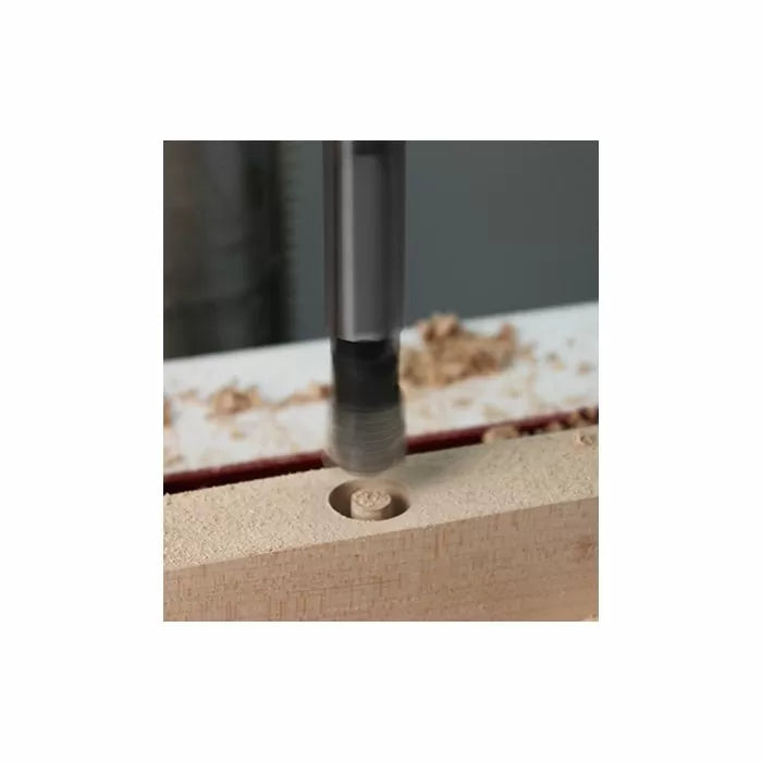 Wood plug cutter bit drilling a hole in a wooden board with wood shavings around