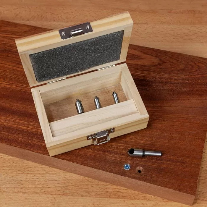 Woodworking countersink drill bit set in wooden case on a workbench with drilled wood piece
