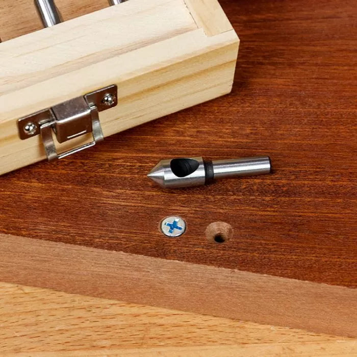 Woodworking countersink drill bit on wood surface next to screw and wooden storage box