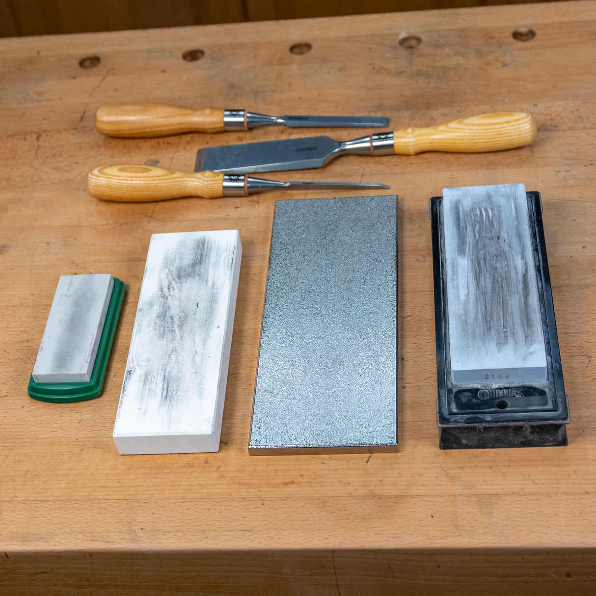 Woodworking chisels and sharpening stones on a workbench for tool maintenance