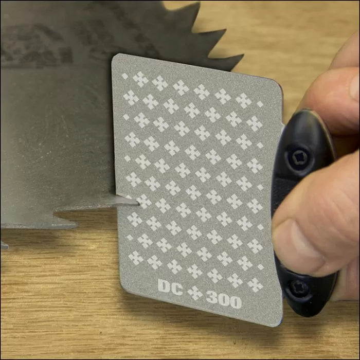 Diamond sharpening card honing a saw blade tooth on a workbench