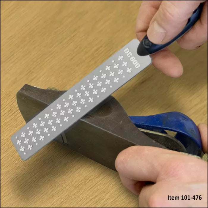 Hand using diamond sharpening stone on wood hand plane blade for woodworking tool maintenance