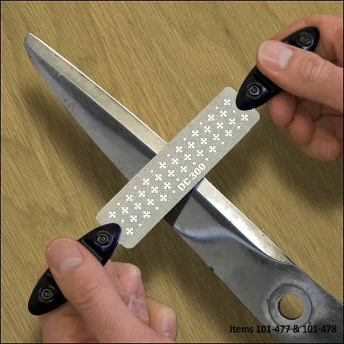 Hand sharpening large scissors with a DC-300 diamond sharpening stone on wood surface.