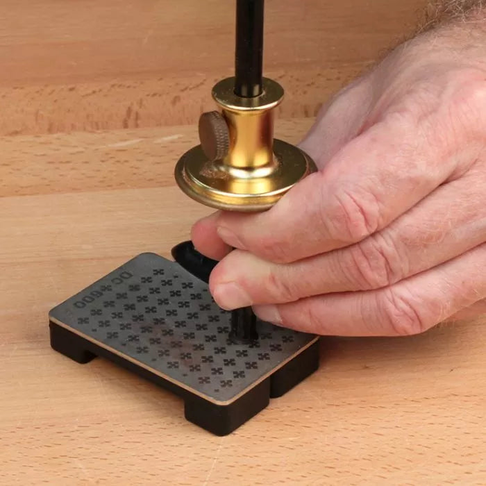 Hand using a brass marking gauge on a dovetail alignment board for precise woodworking