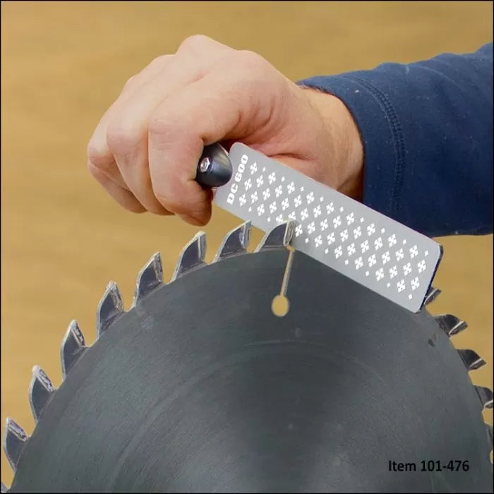 Hand sharpening a circular saw blade tooth with a diamond honing tool for woodworking.