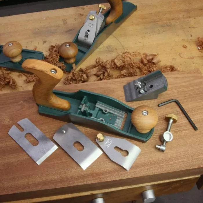 Disassembled bench hand plane with wood handle and metal parts on woodworking bench