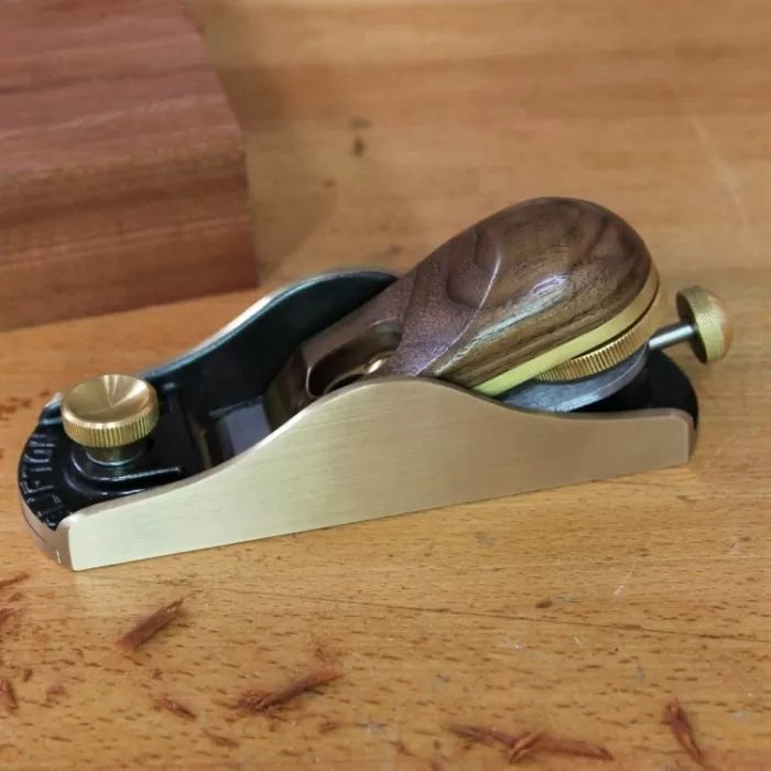Low angle hand plane with brass and wood handle on a woodworking bench
