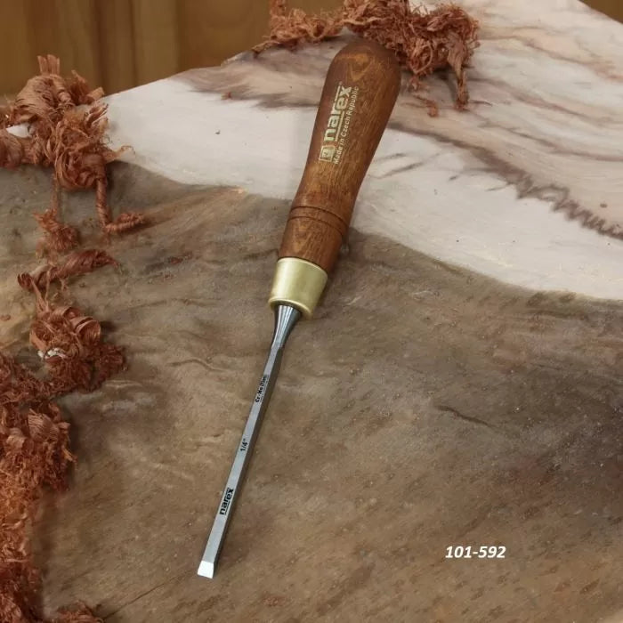 Woodworking chisel with wooden handle resting on unfinished wood with wood shavings