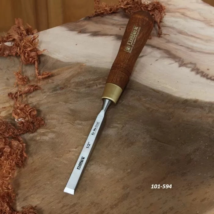 Woodworking chisel with wooden handle and brass ferrule on carved wood surface