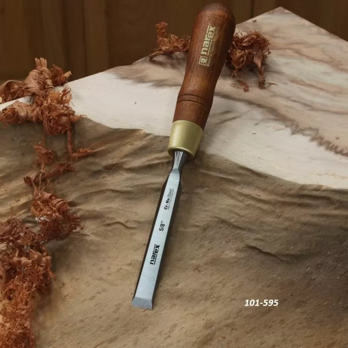 Woodworking chisel with wooden handle on carved wood surface, wood shavings nearby.