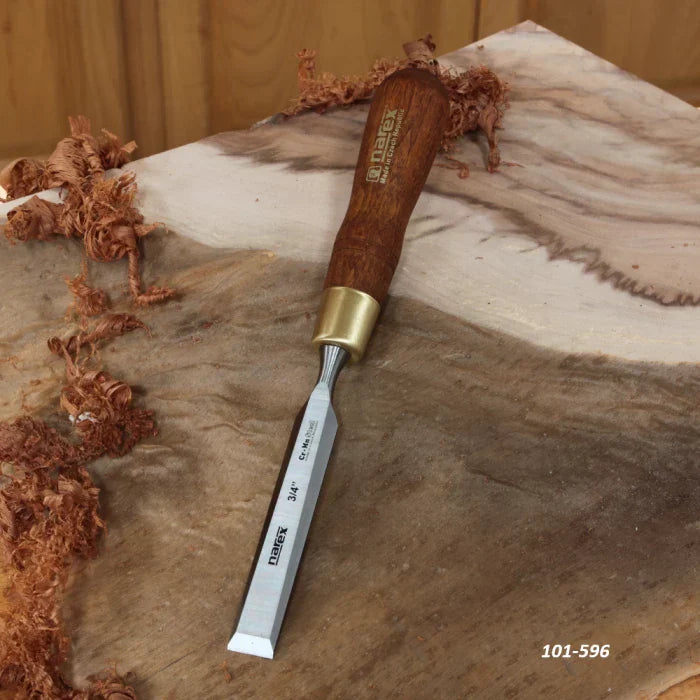 Woodworking chisel with wood handle and brass ferrule on a carved wood surface with shavings