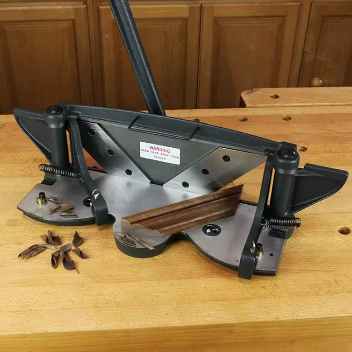 Precision miter trimmer for woodworking on a wooden workbench with trimmed wood pieces