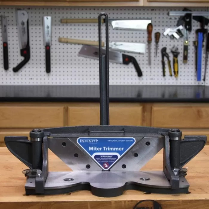 Miter trimmer tool on workbench in woodworking shop with hand tools on pegboard wall
