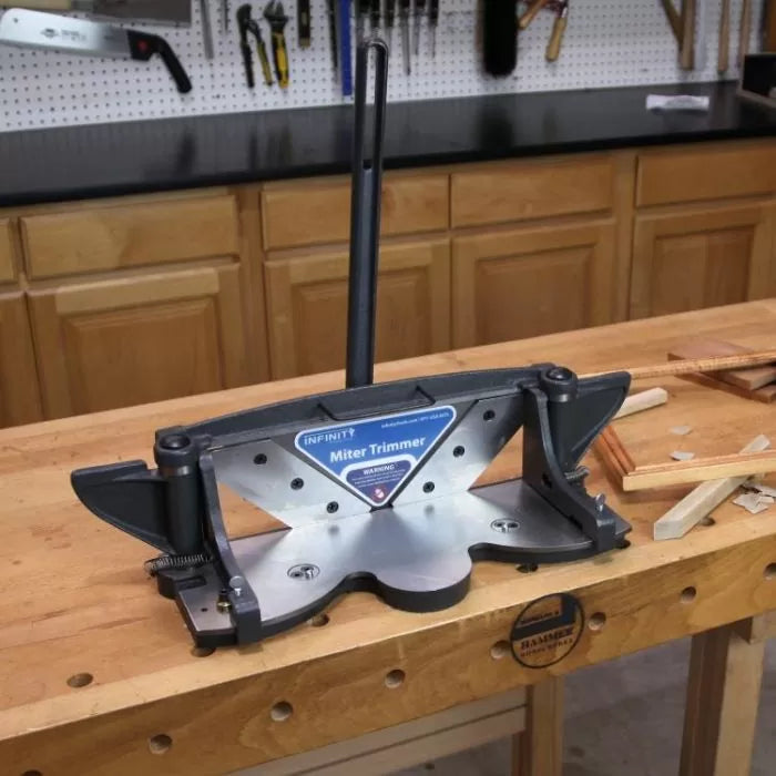 Miter trimmer woodworking tool on workbench surrounded by wood strips in workshop setting