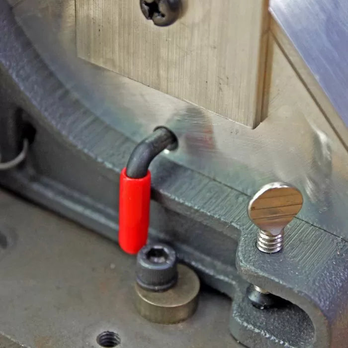 Close-up of woodworking jig metal components with red safety cap and adjustment screw