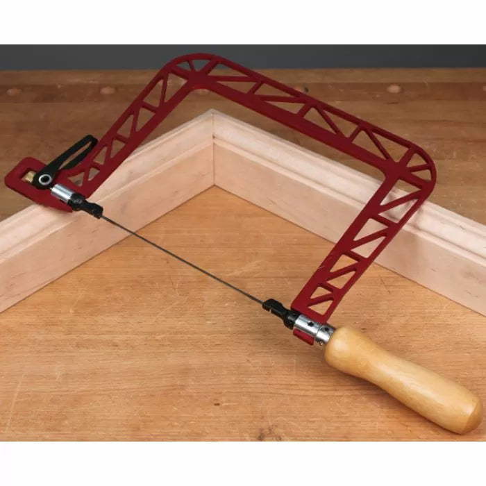 Coping saw with red steel frame and wooden handle on a woodworking bench