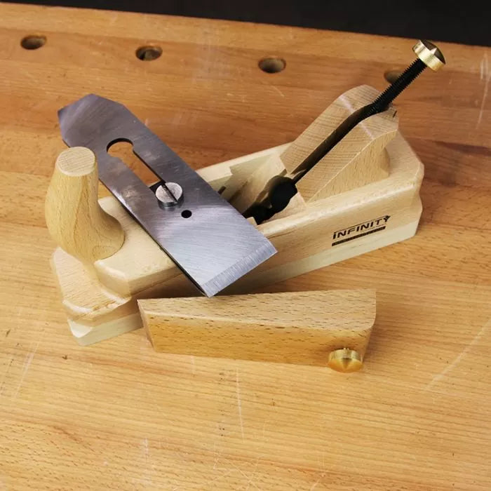 Wooden hand plane with metal blade and components on a workbench, woodworking hand tool