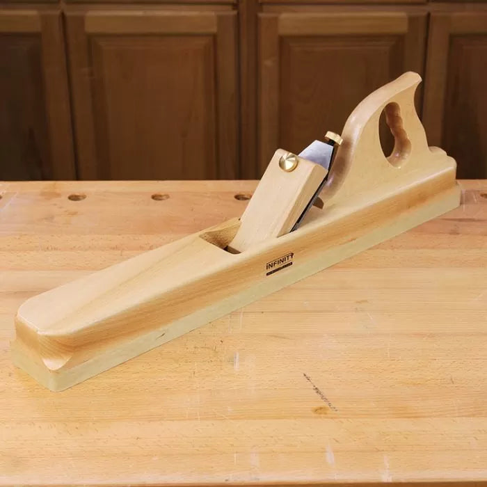 Wooden jointer hand plane on a woodworking bench with cabinet background
