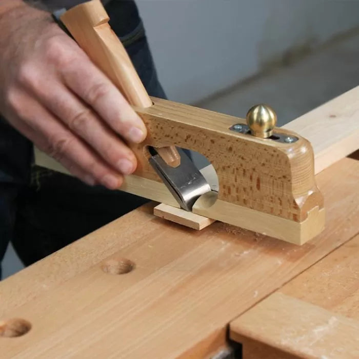 Woodworker using a hand plane tool to smooth wood on a workbench
