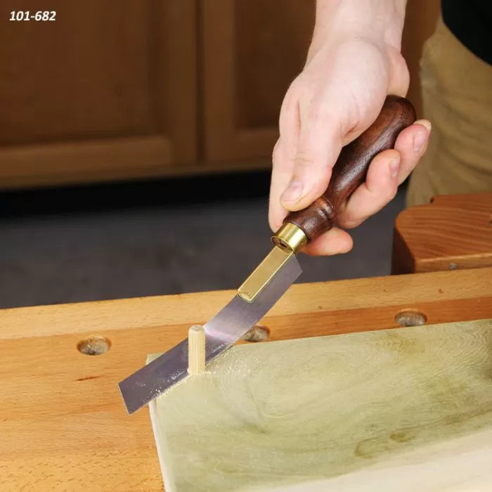 Flush cut saw with wooden handle trimming dowel on workbench, woodworking tool in use