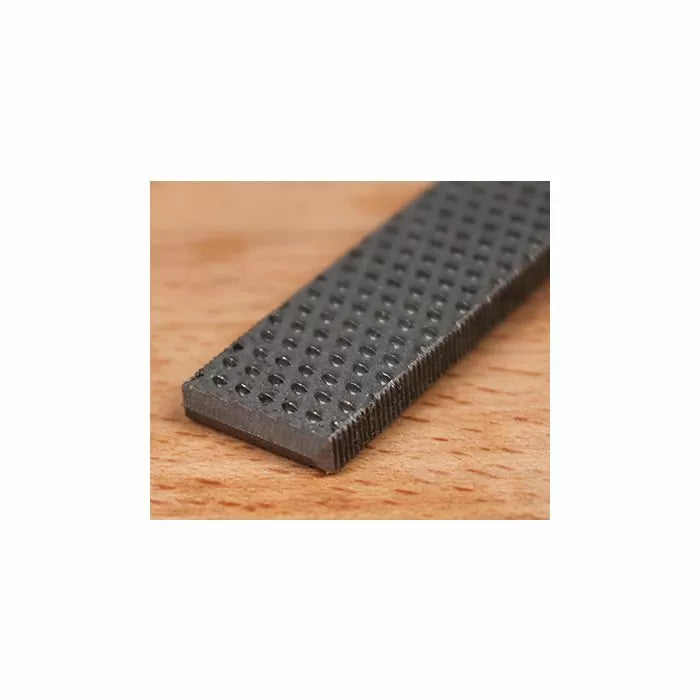 Close-up of a flat metal woodworking rasp on a wooden surface