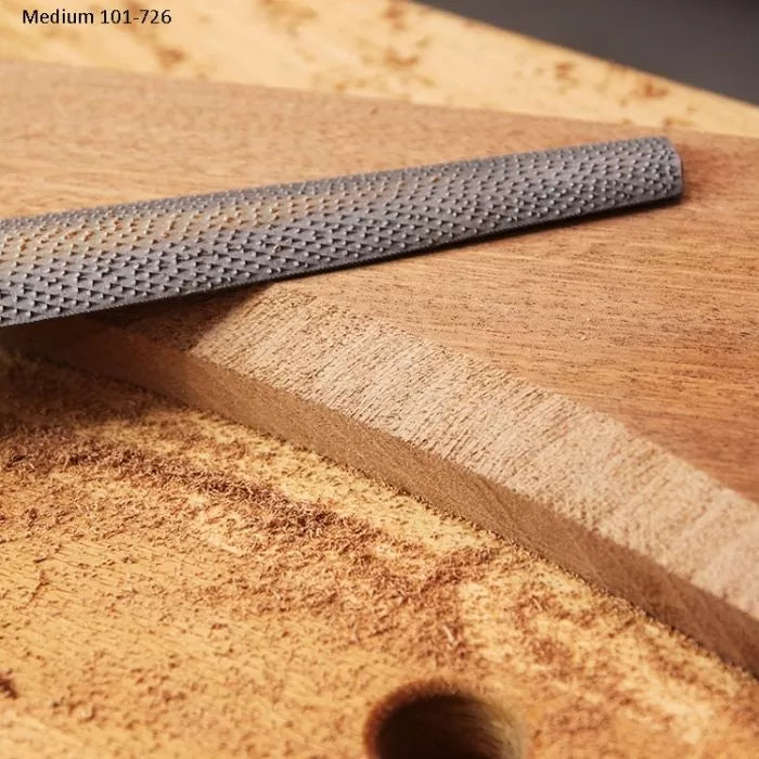 Woodworking rasp file smoothing curved edge of cut wood board with visible grain