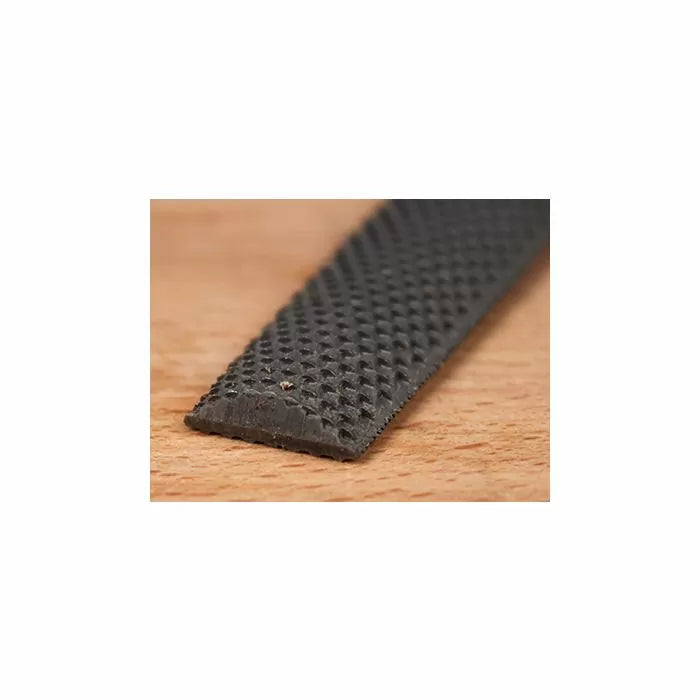 Close-up of a flat woodworking rasp with a textured, coarse surface on a wooden table