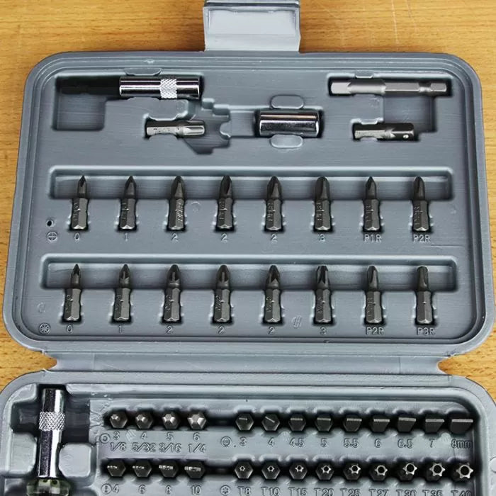 Precision screwdriver bit set with multiple heads and adapters in a gray plastic case on wood.