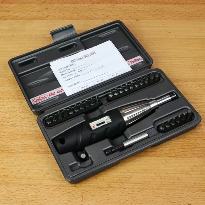 Precision torque screwdriver set with multiple bits in black plastic case on wood surface