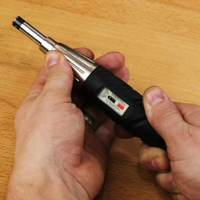 Hands holding an adjustable torque screwdriver on a wooden surface