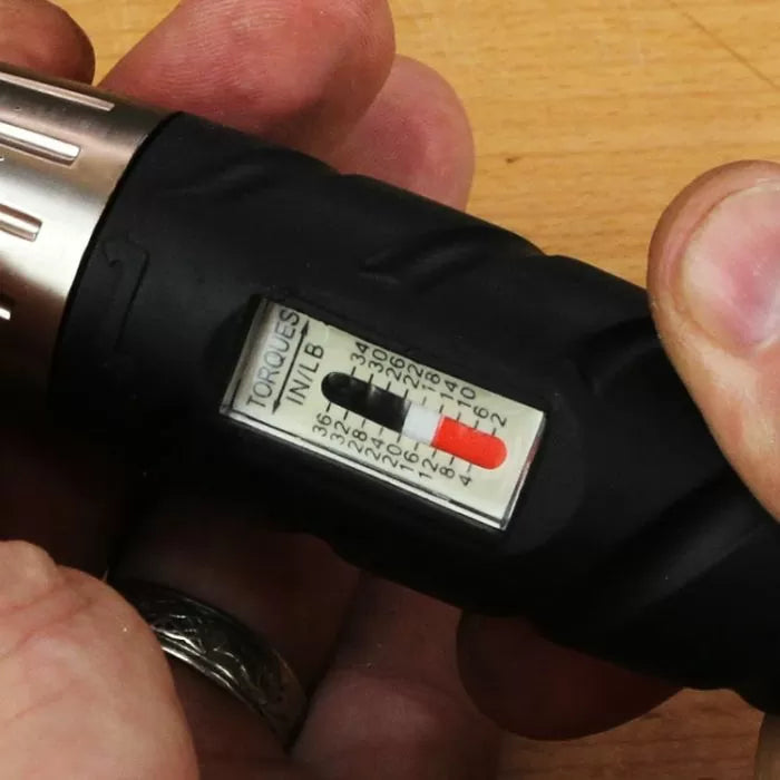 Close-up of adjustable torque screwdriver with inch-pound scale, held in hand on wood surface
