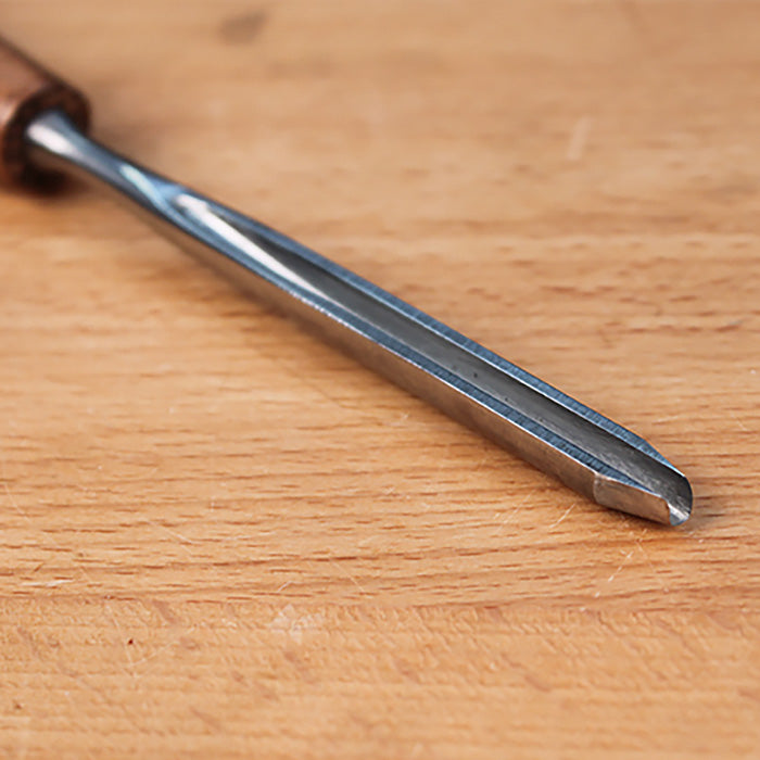 Close-up of a wood carving gouge chisel on a wooden workbench