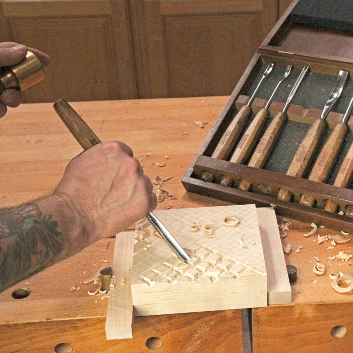 Woodworker carving wood with chisel and mallet, wood carving tools set on workbench