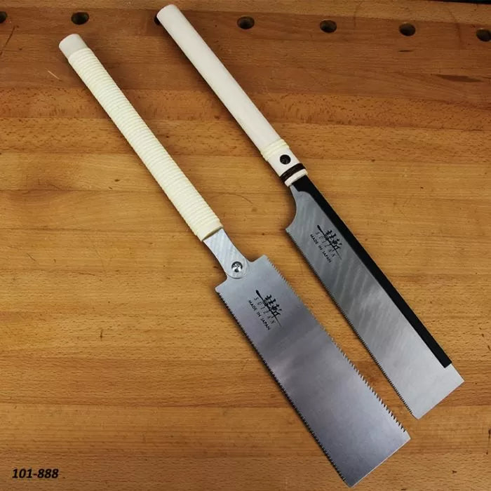 Two Japanese pull saws with white handles on a wooden workbench, precise woodworking tools