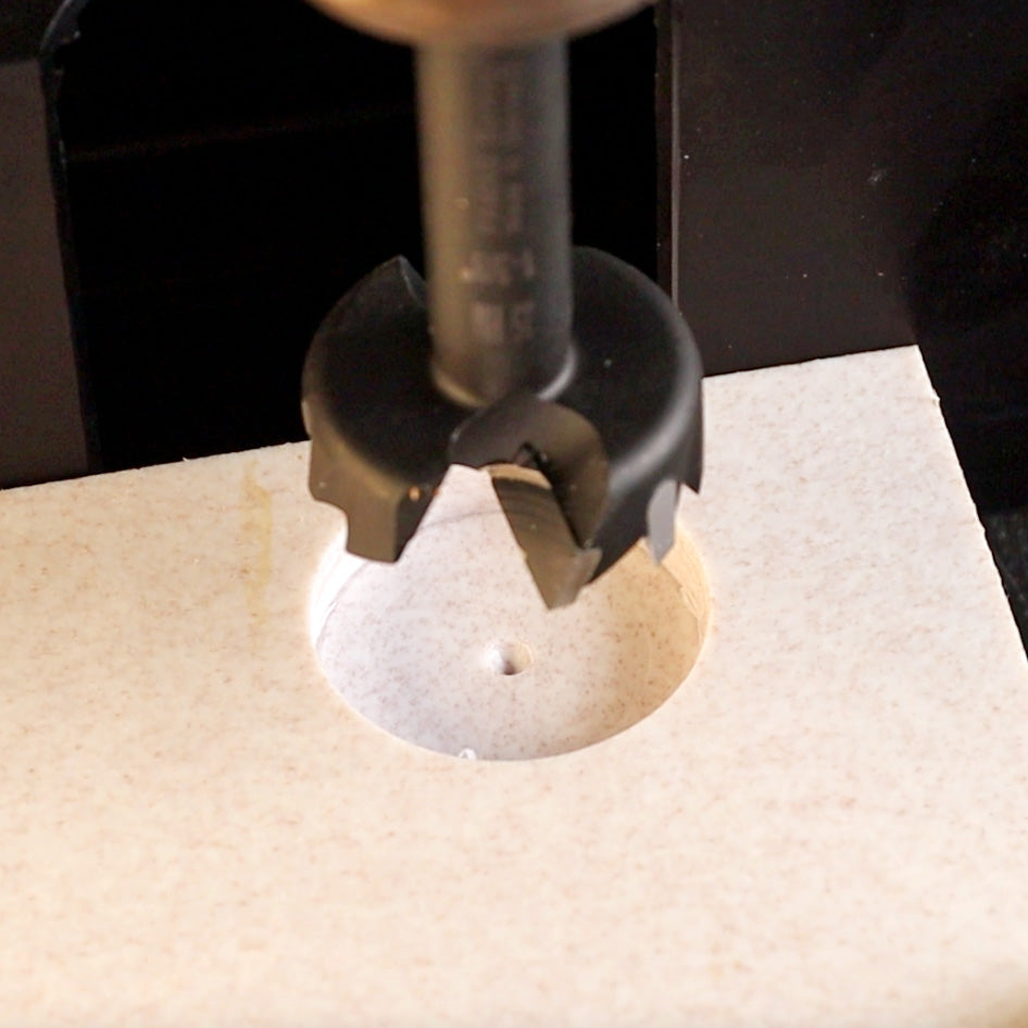 Forstner drill bit cutting a clean hole in light-colored wood panel