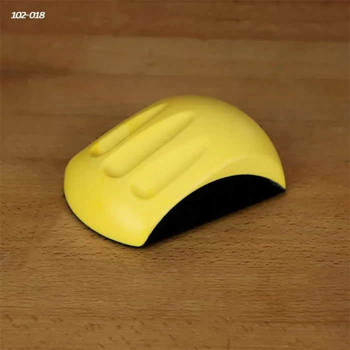 Yellow sanding block hand tool on a wooden surface, woodworking accessory