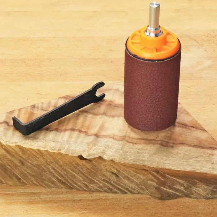 Drum sander attachment and wrench on a carved wood board, woodworking tool accessory