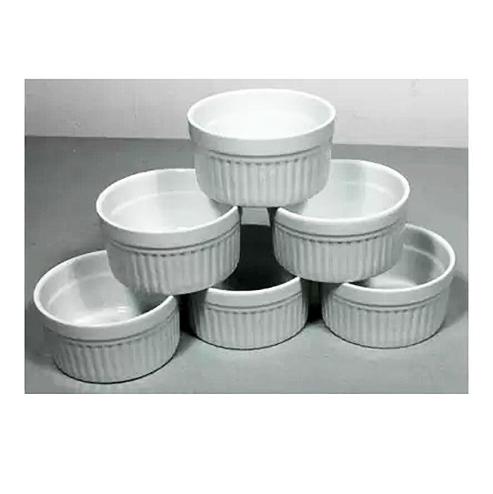 Stack of six white ceramic ramekins with ribbed sides on a gray surface