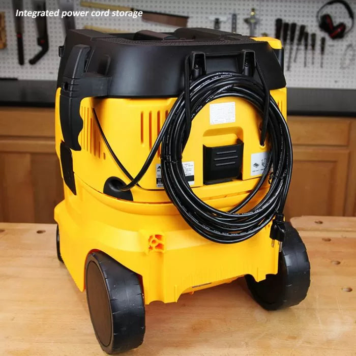 Yellow shop vacuum with integrated power cord storage on workbench in woodworking shop