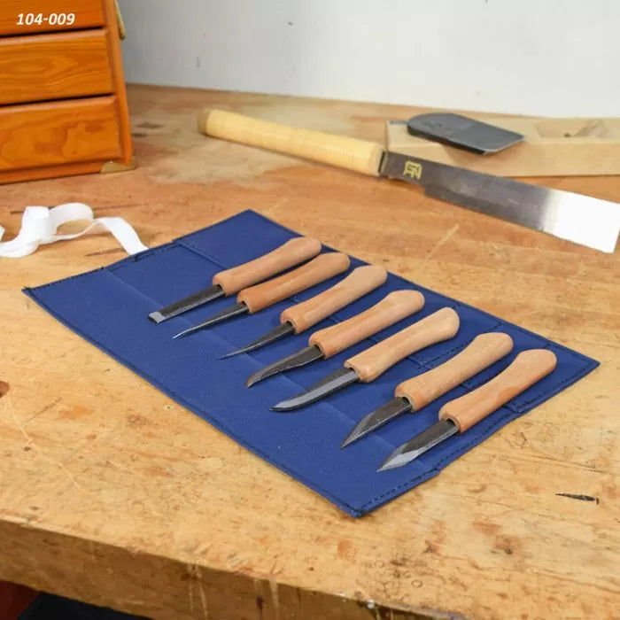 Wood carving knife set with wooden handles in blue roll-up pouch on workbench