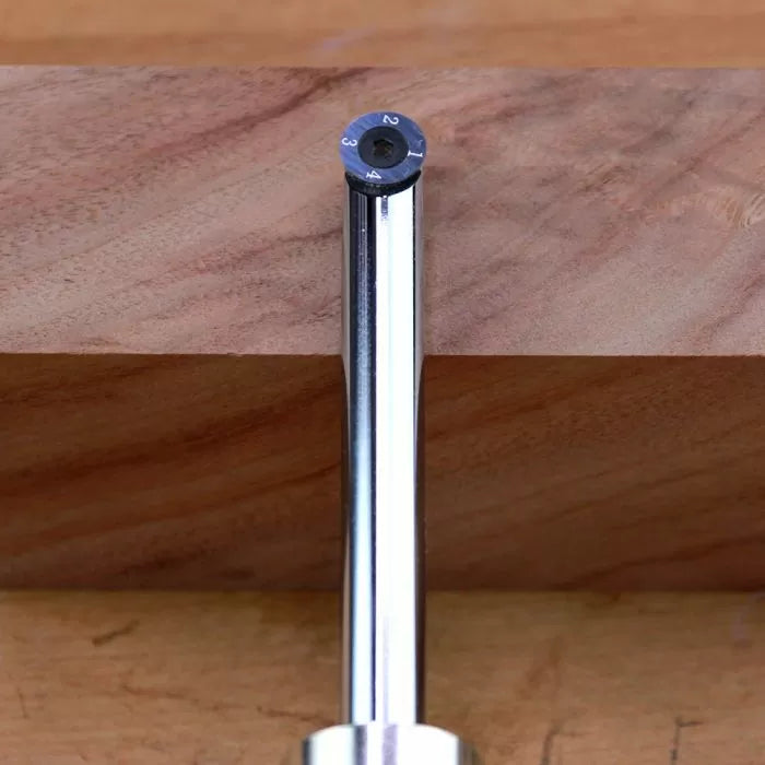 Round carbide insert router bit positioned against a wooden board for woodworking.