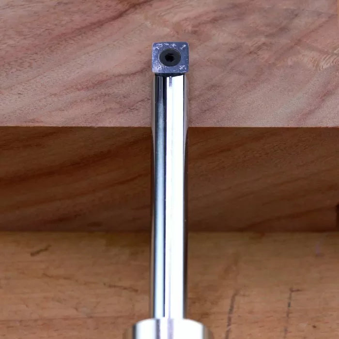 Square carbide insert router bit on wood surface for woodworking precision cutting