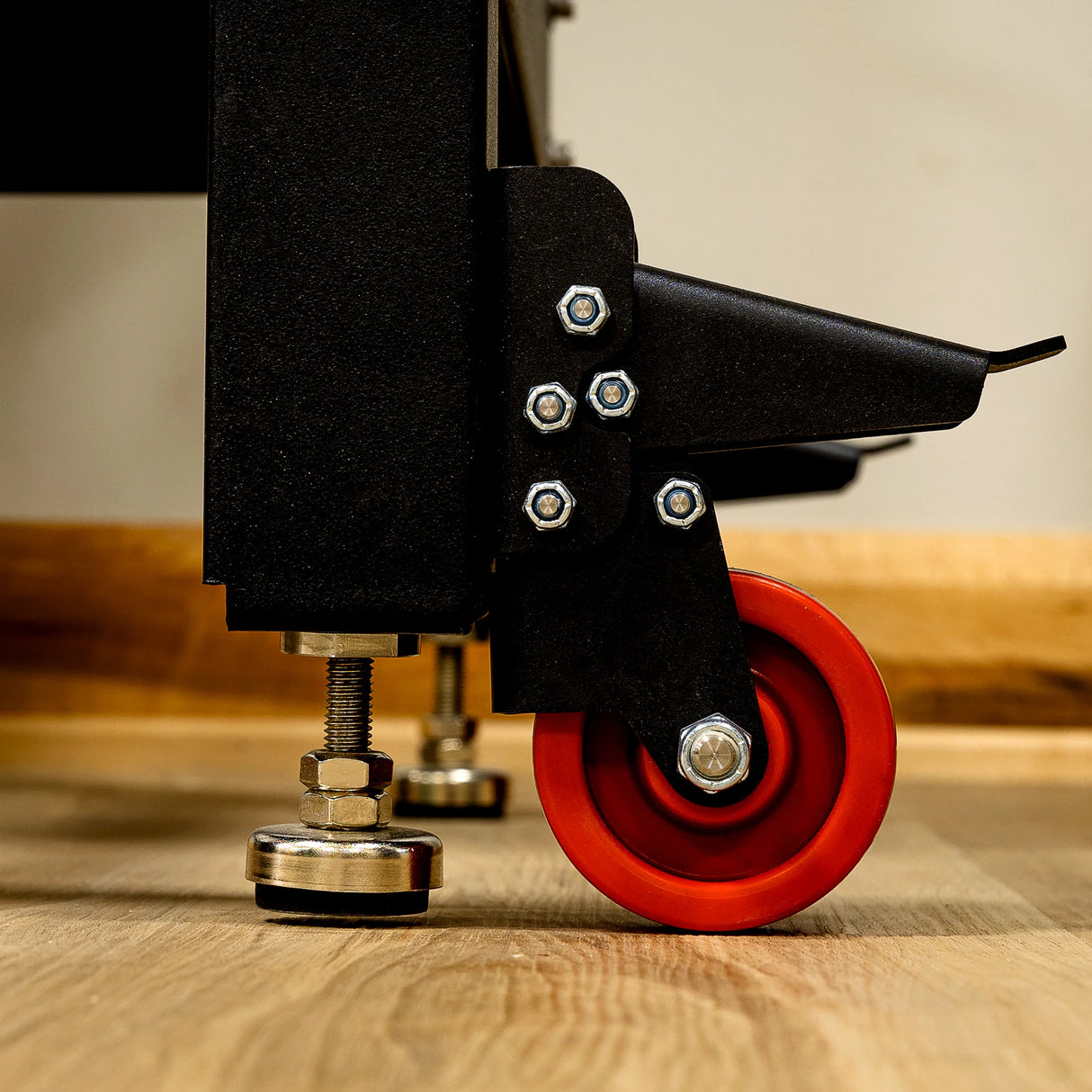 Close-up of adjustable caster wheel and leveling feet on heavy-duty woodworking router table.
