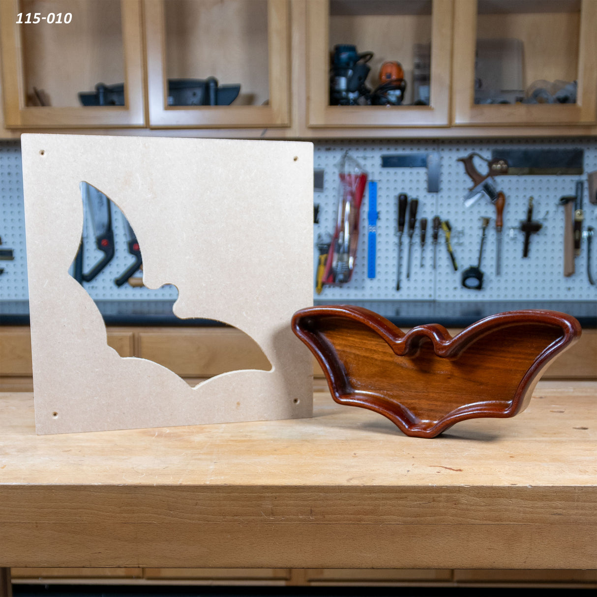 Bat-shaped woodworking tray and matching MDF template on workbench in woodshop