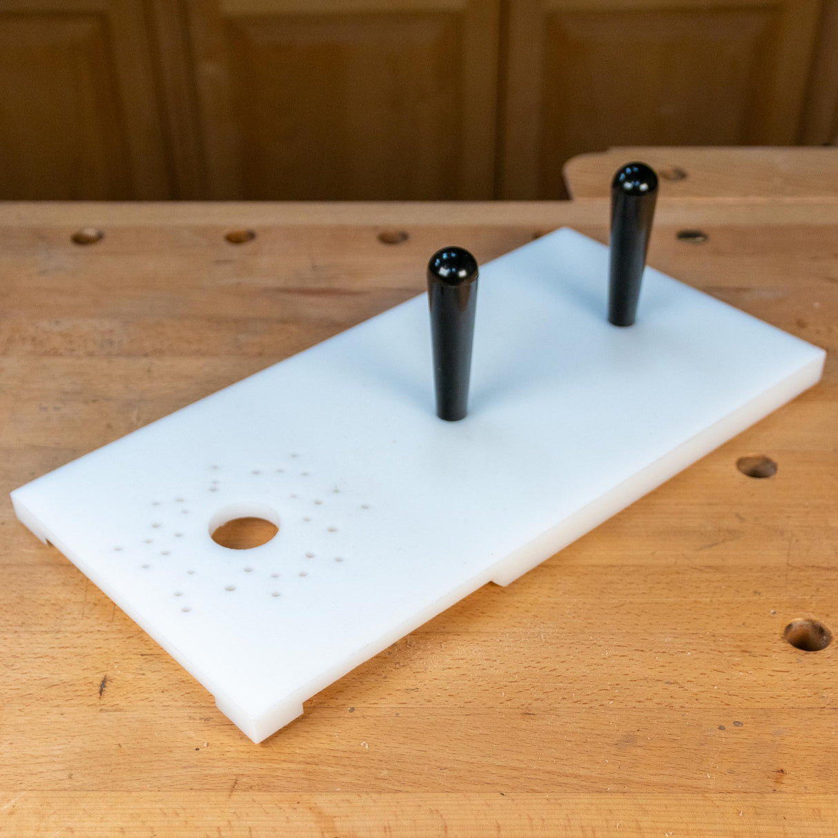 Router table jig with dual handles and pre-drilled holes on a woodworking bench