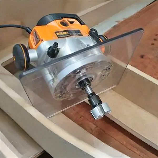 Woodworking router with straight bit cutting groove in plywood board