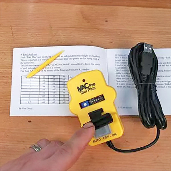 VAC Pro Tool Plus switch on wooden table with USB cable, instruction manual, and yellow tool