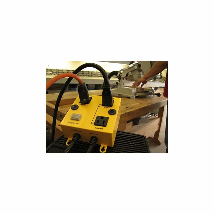 Yellow automatic power switch for woodworking tools on a workshop table with saw in background