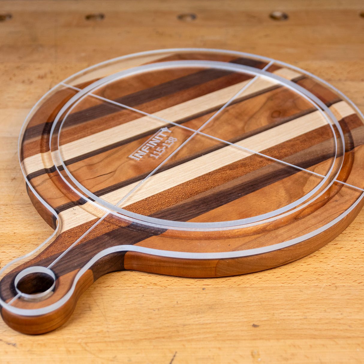 Acrylic cutting board template overlay on round striped wooden cutting board with handle